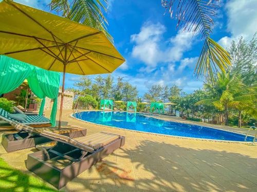 a swimming pool with chairs and umbrellas next to a resort at Long Hải Channel Beach Resort in Long Hai