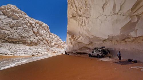 a man standing in the desert next to a large rock at Rahala Safari Hotel in Qasr Al Farafirah