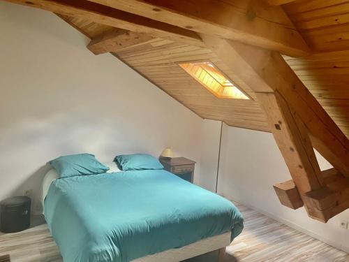 a bedroom with a blue bed in a attic at Super appartement loué meublé tout équipé in Saint-Claude