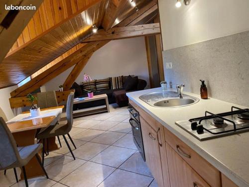 une cuisine avec un évier et une cuisinière dans une pièce dans l'établissement Super appartement loué meublé tout équipé, à Saint-Claude