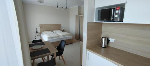 Habitación pequeña con cama y mesa con sillas. en Apartamenty ELIASZ, en Ustronie Morskie