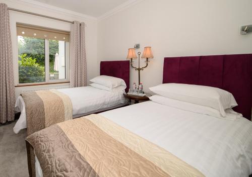 two beds in a hotel room with a window at Ashville House B&B Tralee in Tralee