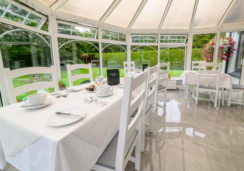 Ashville House B&B Tralee في ترالي: غرفة طعام بيضاء مع طاولات وكراسي بيضاء