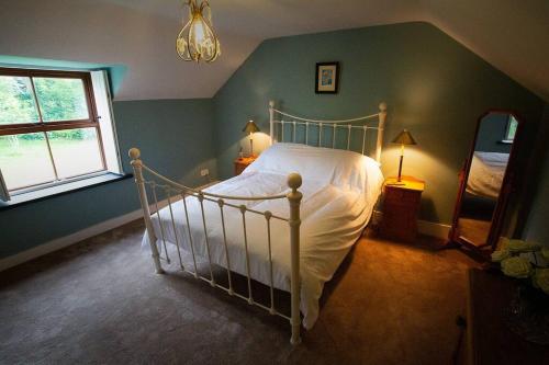 a bedroom with a white bed in a room with a window at Cosy Cottage in Wild Countryside by Llys-y-Fran in Pembrokeshire