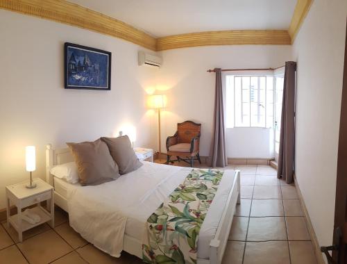 a bedroom with a bed and a chair and a window at Villa Osiris in Flic-en-Flac