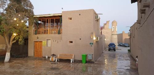 un edificio con un banco en una calle de ladrillo en KHIVA ABDULLA Guest House en Khiva