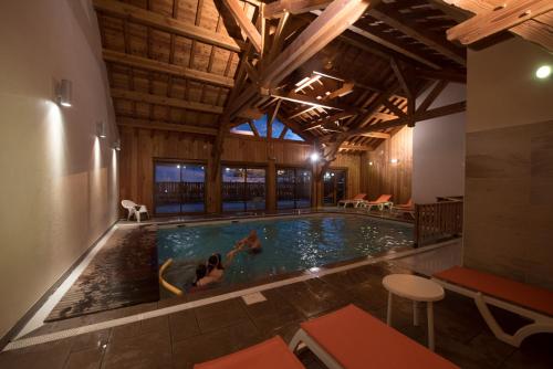 une piscine dans un immeuble avec deux personnes qui nagent dans l'établissement Hôtel Soleil des Neiges, au Sauze