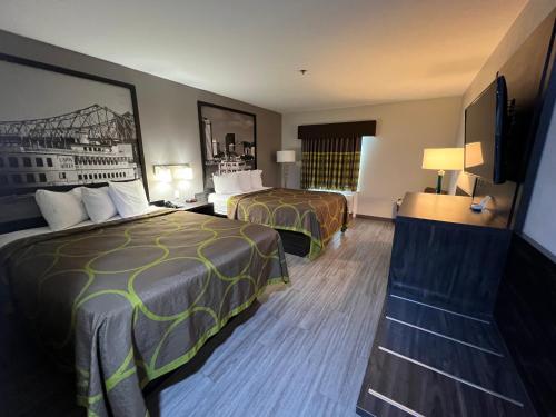 a hotel room with two beds and a tv at Super 8 by Wyndham Lake Charles/Sulphur in Lake Charles