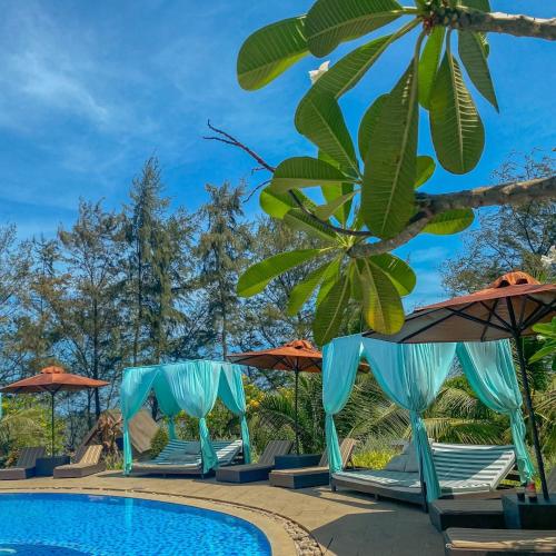 a group of chairs and umbrellas next to a pool at Long Hải Channel Beach Resort in Long Hai
