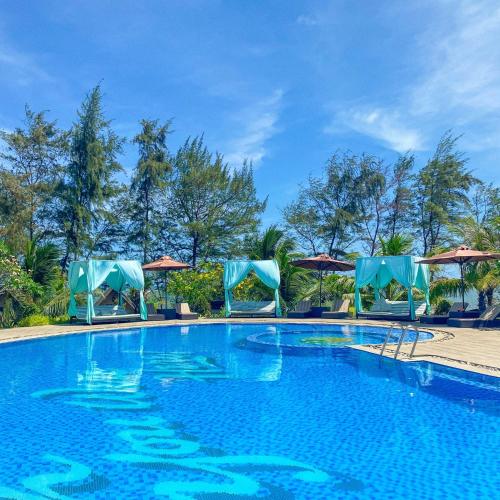 a large swimming pool with chairs and umbrellas at Long Hải Channel Beach Resort in Long Hai