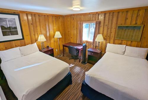 a bedroom with two beds and a desk with a piano at Teton Court Motel in Pinedale