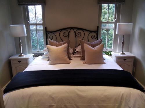 a bedroom with a large white bed with two windows at Tranquil Tokai in Tokai