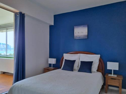 - une chambre avec des murs bleus et un lit avec deux lampes dans l'établissement Spacieux appartement vue mer panoramique & parking, à Marseille