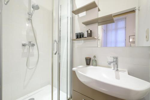 a white bathroom with a sink and a shower at Magnificent 2 bedroom duplex + terrace Ixelles in Brussels