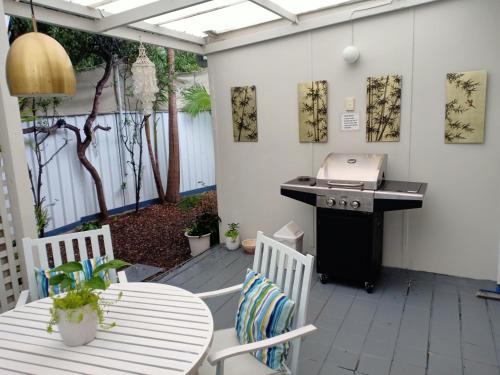 a patio with a grill and two tables and chairs at The Boathouse a 3 Bedroom House in Narooma
