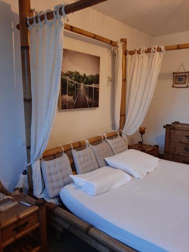 Cette chambre comprend un lit avec des oreillers et des rideaux blancs. dans l'établissement LA GRAN'EXOTIQUE, à Nouvion-en-Ponthieu