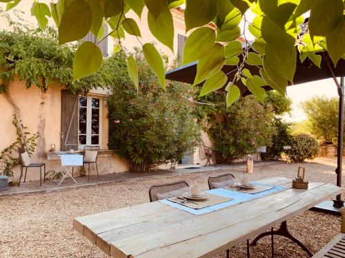 una mesa de picnic de madera en un patio con sillas en Le Vieux Portail, en Saint-Saturnin-lès-Apt