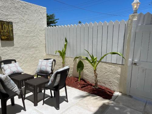 a patio with four chairs and a white fence at #6 Ferguson Rd - Townhouse in Nassau