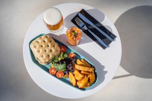 a white table with a plate of food and a glass of beer at Occidental Puerto Banús in Marbella