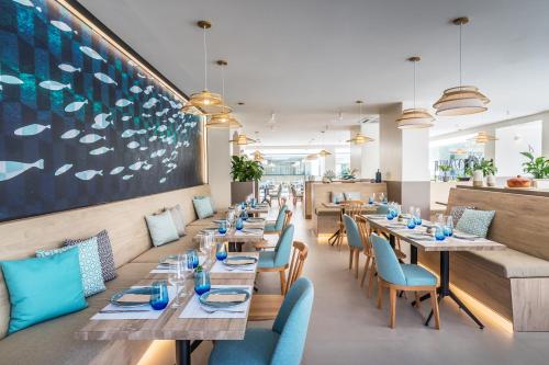 a restaurant with wooden tables and blue chairs at Occidental Puerto Banús in Marbella