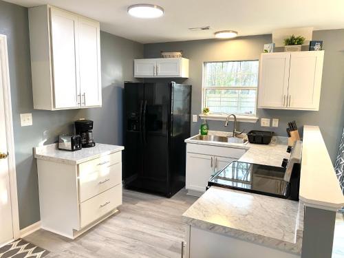 a kitchen with white cabinets and a black refrigerator at The Great Escape With Friends & Family & Pets!!! in Jacksonville