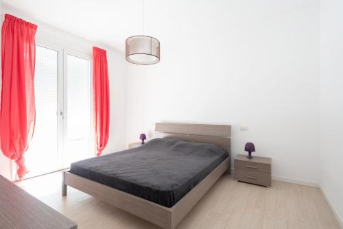 um quarto branco com uma cama e cortinas vermelhas em Finisterrae 1 em Lido di Jesolo