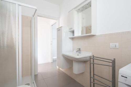 uma casa de banho branca com um lavatório e um chuveiro em Finisterrae 1 em Lido di Jesolo