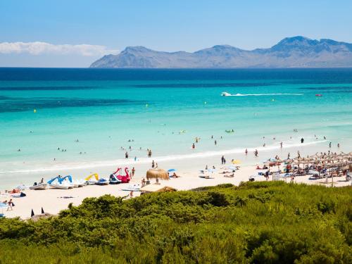 a group of people on a beach with the ocean at Aparthotel Dunes Platja in Can Picafort