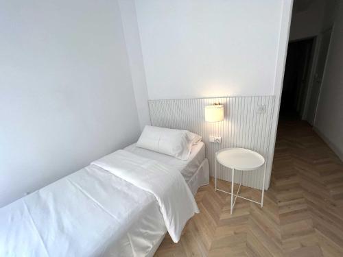 a small bedroom with a white bed and a table at The MO GOTIC in Barcelona