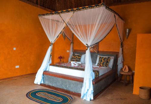 a bedroom with a bed with a mosquito net at Kusini beach bungalows in Kizimkazi