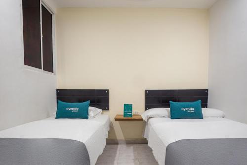 two beds with blue pillows in a room at Ayenda Hotel Alejandría in Montería
