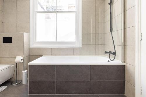 uma casa de banho com uma banheira e uma janela em Discounted Pure Luxury By Nobu Hotel em Londres