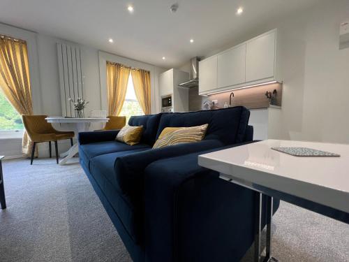 a living room with a blue couch and a kitchen at Winckley Square Residences in Preston