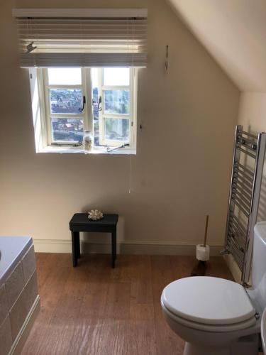 a bathroom with a toilet and a window and a table at Shining Star, Cartway River Views in Bridgnorth