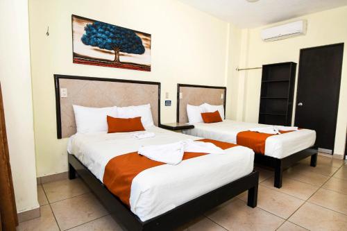 um quarto de hotel com duas camas com lençóis laranja e branco em Hotel los faroles em Ocozocuautla