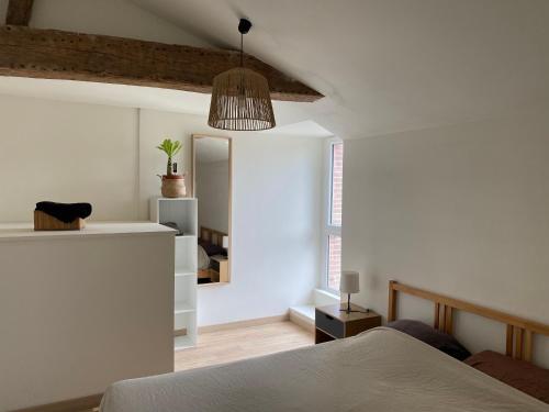 Habitación blanca con cama y espejo en Charmant appartement avec SPA, en Fontenay-le-Comte