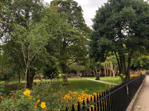 a fence in a park with flowers and trees at Winckley Square Residences in Preston