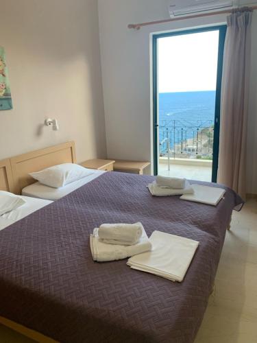 um quarto com 2 camas e uma grande janela em Iro Hotel em Agía Galíni