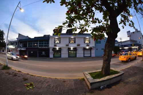 a building on a street with cars parked on the road at La Maja Suites in Villahermosa