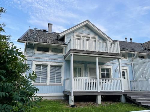 a blue house with a porch and a balcony at Pan Golf & Spa Villas in Imatra