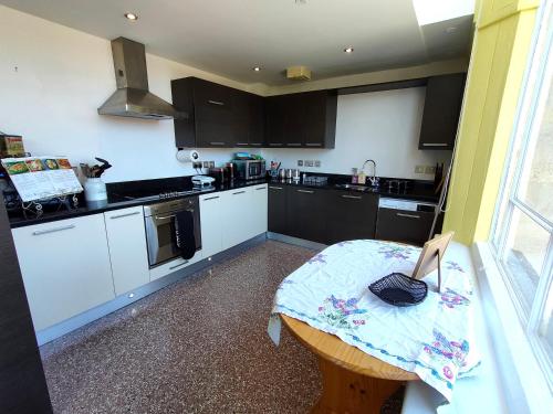 una cocina con una mesa pequeña y una cocina con armarios negros en Stunning 2-bed Listed Apartment in Taunton's historic centre, en Taunton