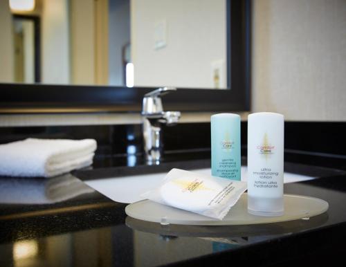 a bathroom counter with two towels and two products on it at Comfort Inn Boucherville in Boucherville