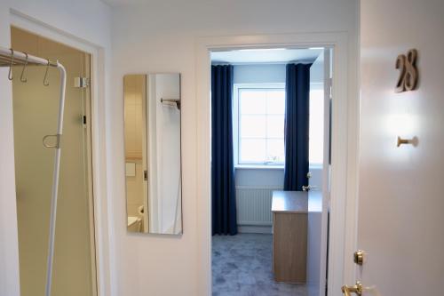 a bathroom with a mirror and a window with blue curtains at Skagen Harbour Hotel in Skagen