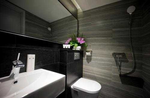 a bathroom with a sink and a toilet and a mirror at Venue Hotel The Lily in Singapore