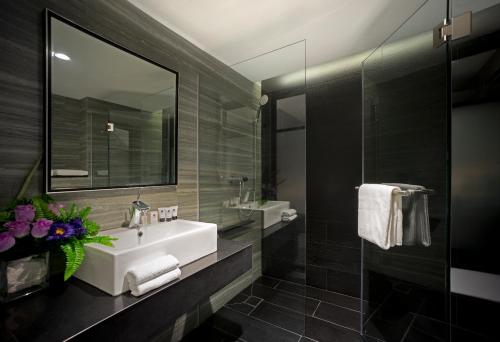 ein Badezimmer mit einem weißen Waschbecken und einem Spiegel in der Unterkunft Venue Hotel The Lily in Singapur