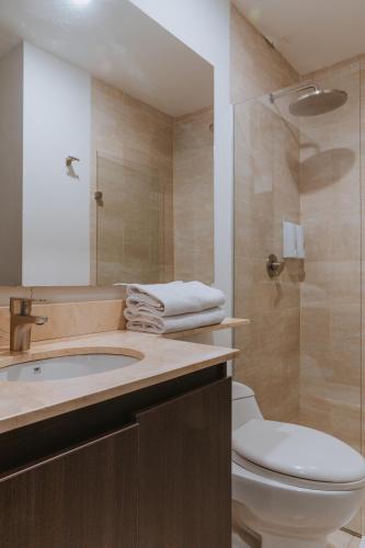 a bathroom with a toilet and a sink and a shower at Travelers Rio Verde Living Suites in Rionegro