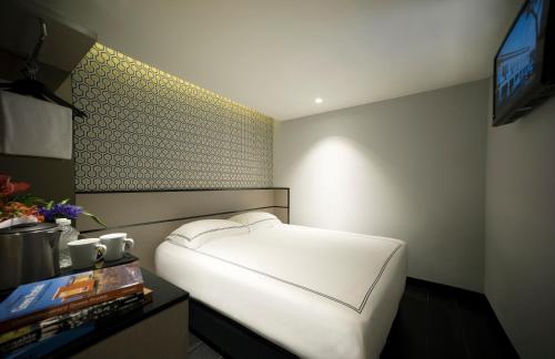 a bedroom with a white bed and a tv at Venue Hotel The Lily in Singapore