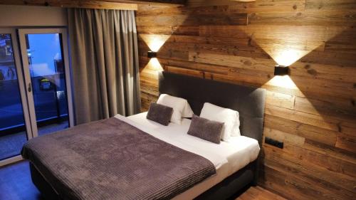 a bedroom with a wooden wall with a bed and lights at Appartments Das Franzal in Zell am Ziller