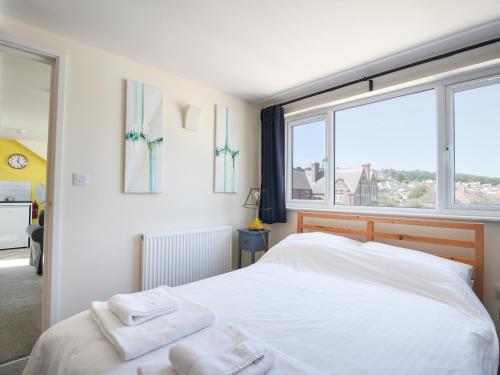 una camera da letto con un letto bianco e asciugamani di Ayla a Lyme Regis