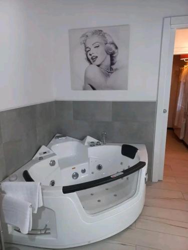 a white bath tub in a bathroom with a picture of a woman at Notte Rosa Suites & Relax in Fornovo di Taro